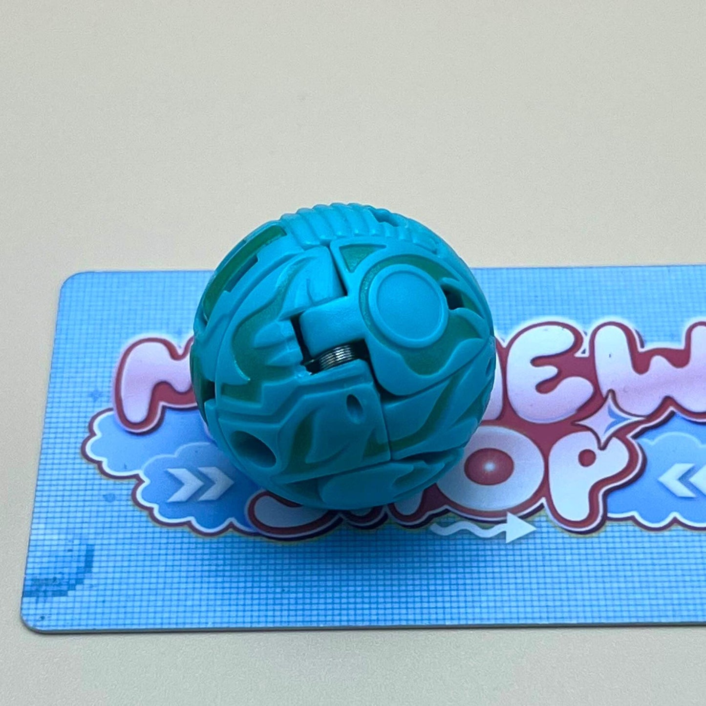 A blue and green toy ball is sitting on a blue and white checkered surface.