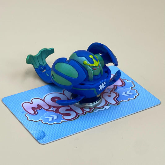 A toy figure of a blue and green sea creature is sitting on a blue card with a cartoon-style design.