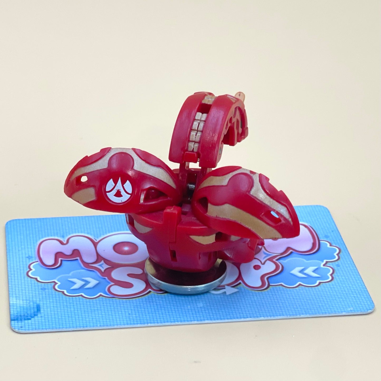 A red and white toy with a face on it, sitting on a blue and white checkered surface.