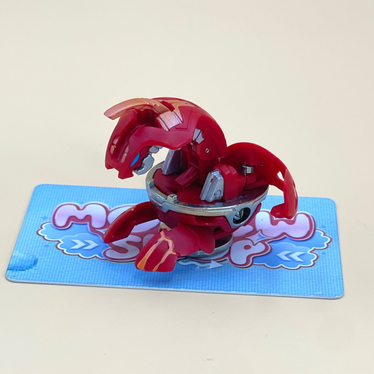 A red toy figure is sitting on a blue and white checkered surface.