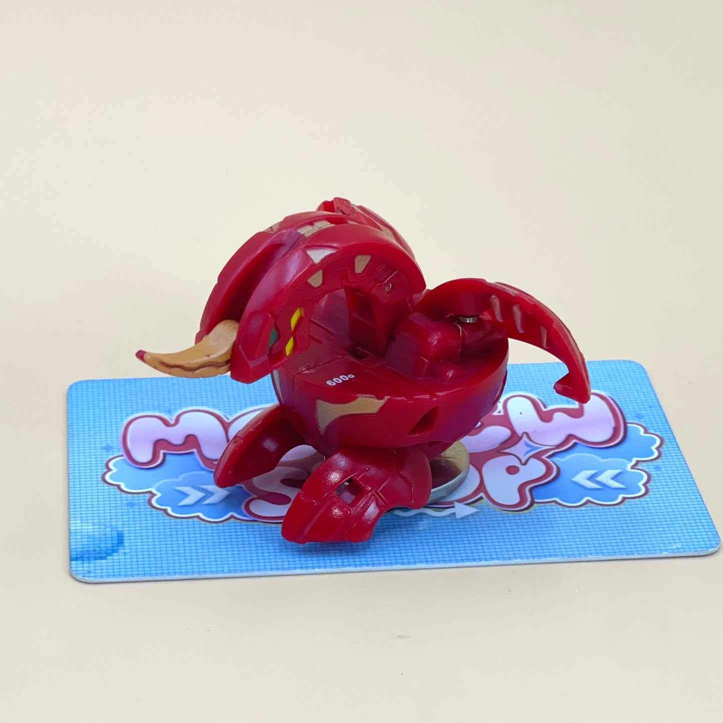 A red toy with a yellow head is sitting on a blue and white checkered surface.
