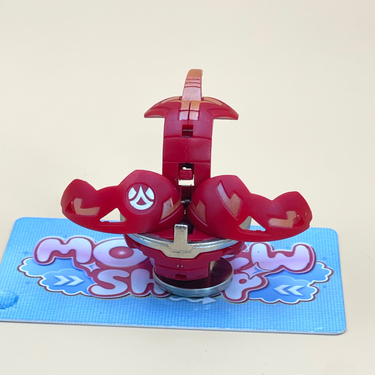 A red toy with a white logo is sitting on a blue surface with a patterned design.