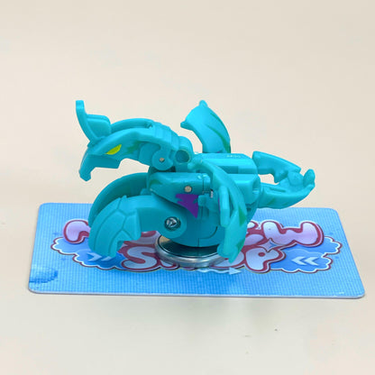 A blue toy robot with a yellow head is sitting on a blue and pink checkered card.