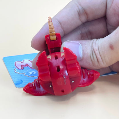 A hand is holding a red toy with a yellow horn, which appears to be a toy car or toy vehicle.