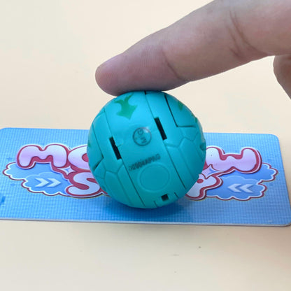 A hand is holding a small, light blue ball with a green design on it, which is placed on a blue and pink card.