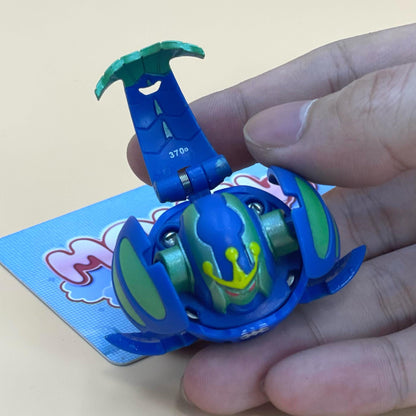 A hand is holding a blue and green toy with a yellow and green design, which appears to be a toy or figurine.