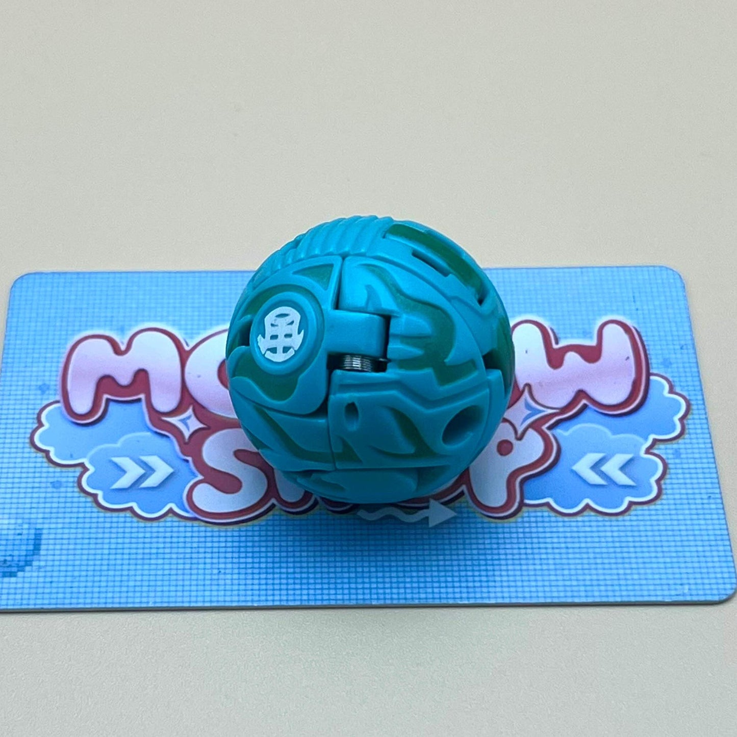 A blue and green toy ball is sitting on a blue and white checkered surface.