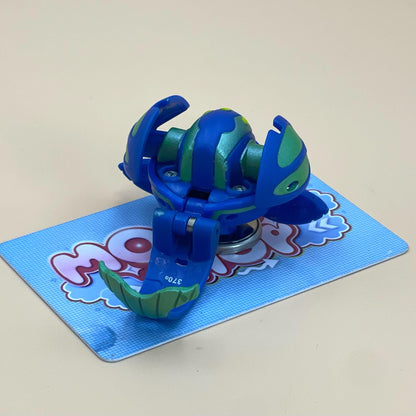A blue and green toy figure is sitting on a blue and white checkered card.