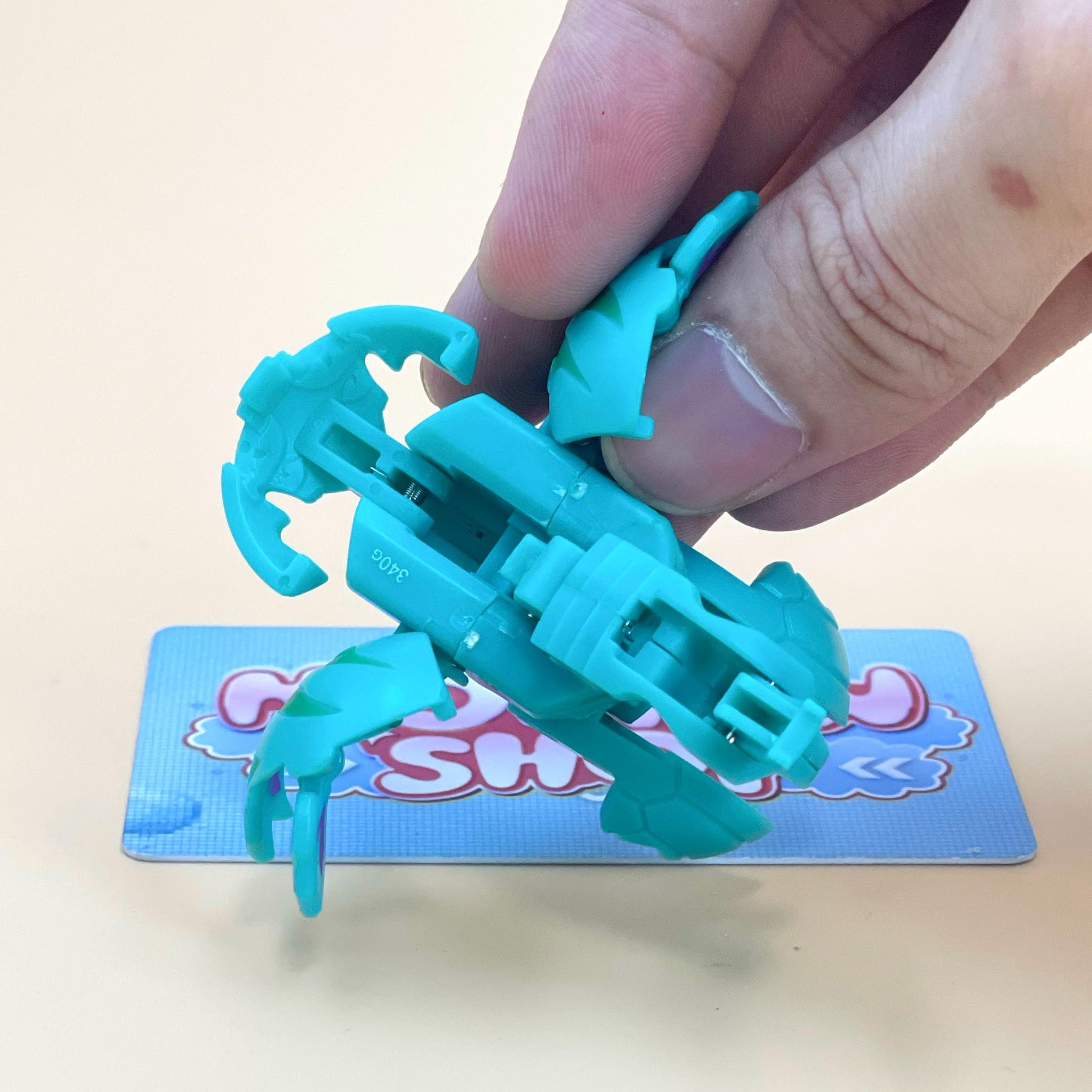 A hand is holding a small toy in a light blue color, which appears to be a toy car or vehicle.