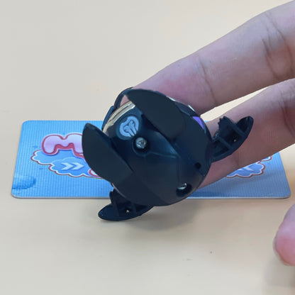 A person's hand is holding a black toy with a heart-shaped cutout on it, which appears to be a toy car or a small toy.