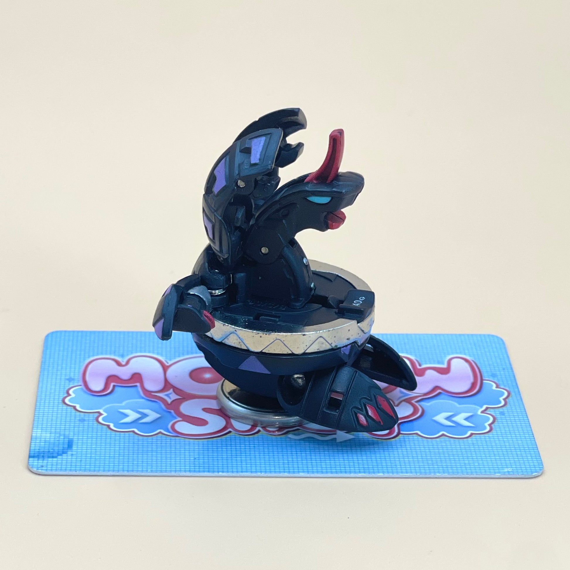 A toy resembling a snake or cobra with a black and purple color scheme is sitting on a blue and white checkered surface.