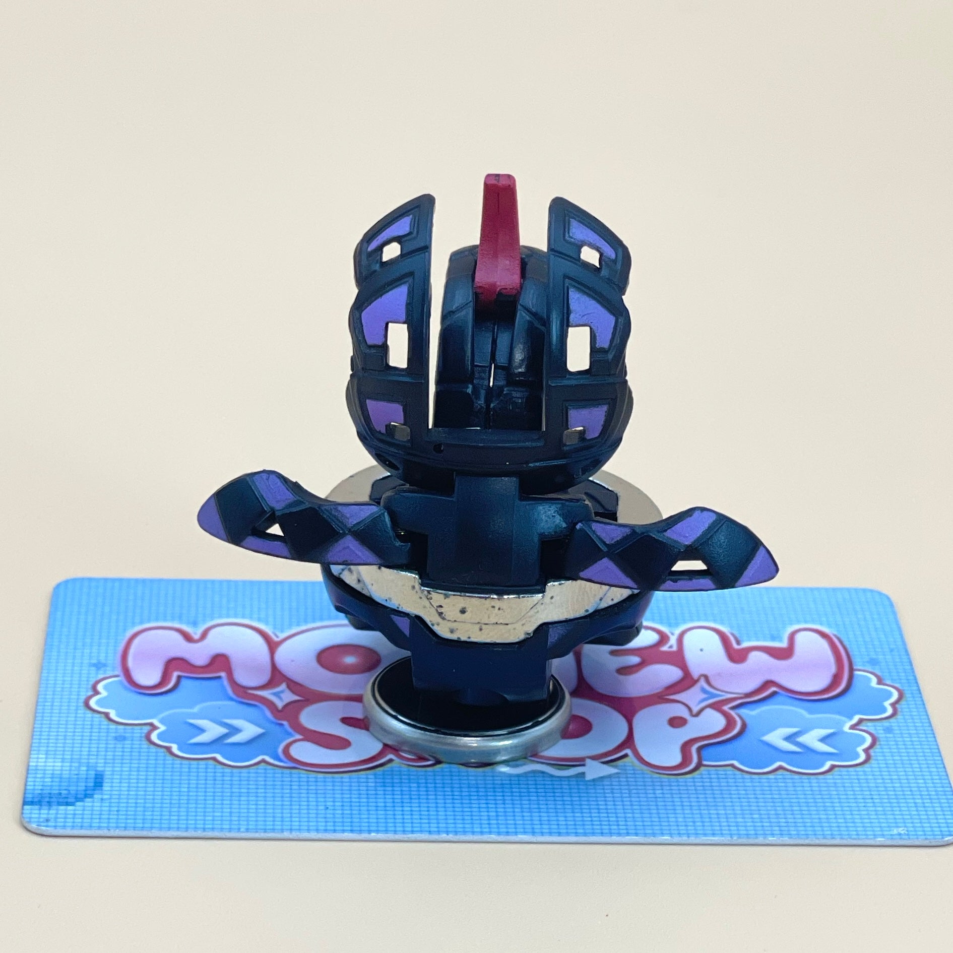 A toy figure with a unique design, featuring a combination of purple and black colors, is placed on a blue and white patterned surface.