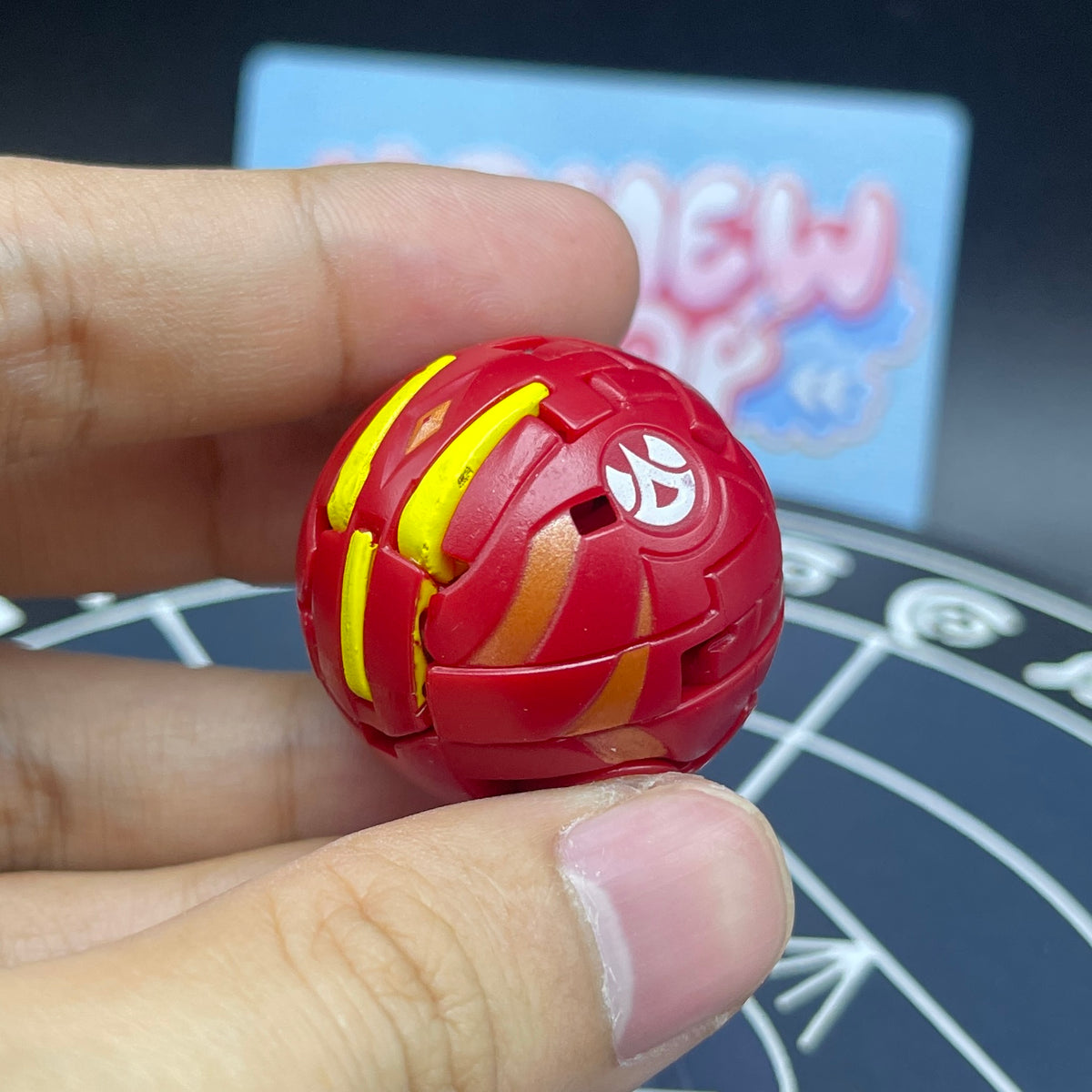 Hand holding Pyrus Neo Dragonoid closed in sphere form displaying yellow accents and Pyrus attribute symbol   