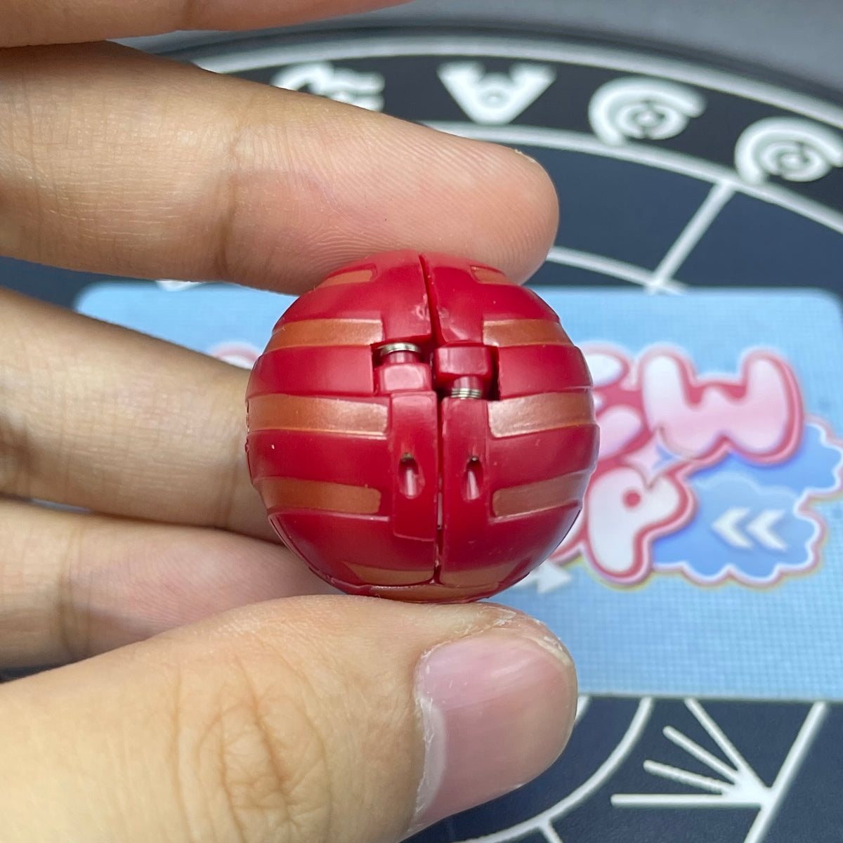 Closed sphere mode of Pyrus B1 Griffon Bakugan showing red pattern lines on sphere surface.