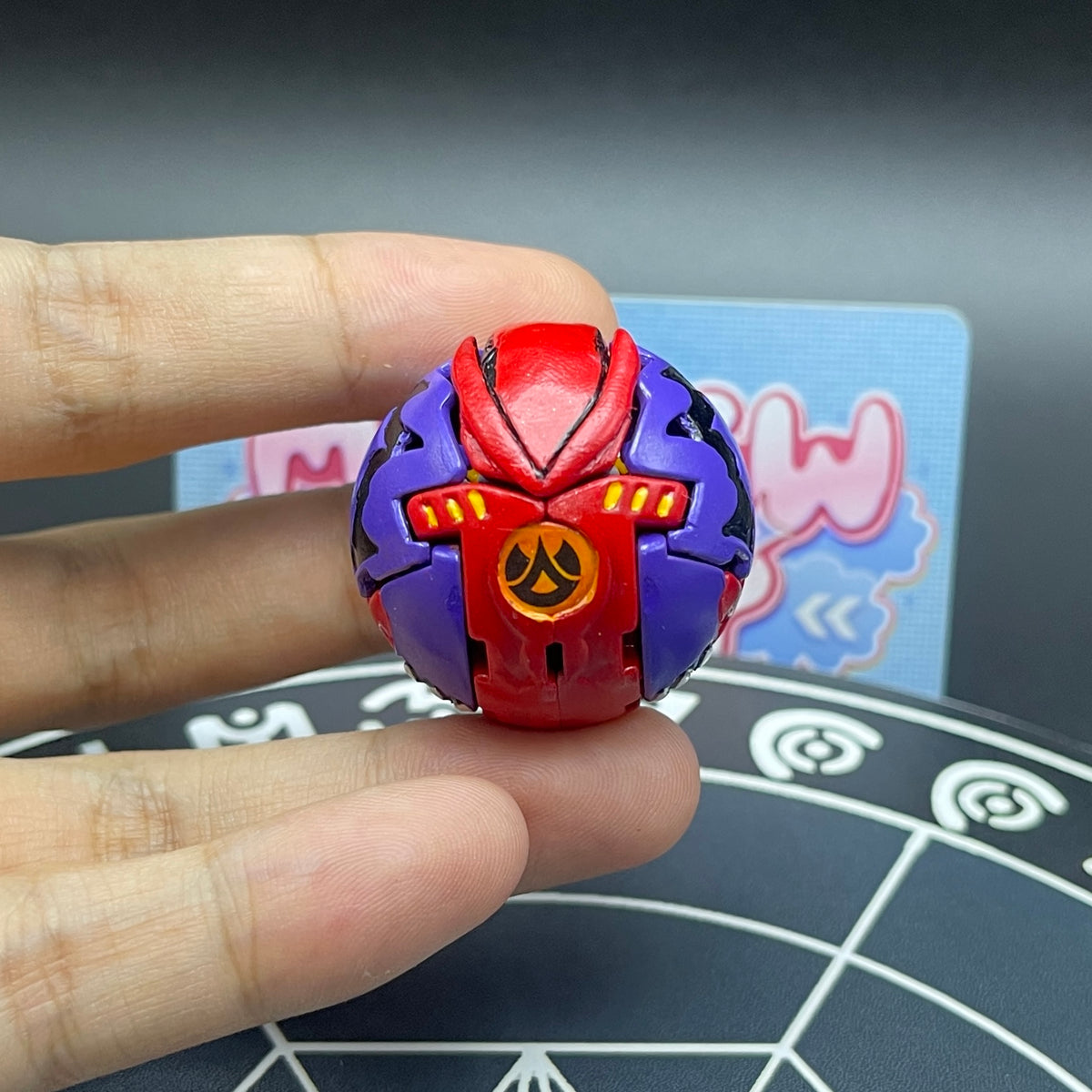 Custom painted Druman Bakugan in ball form held in hand for scale and display.